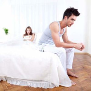 unhappy man sitting on edge of bed